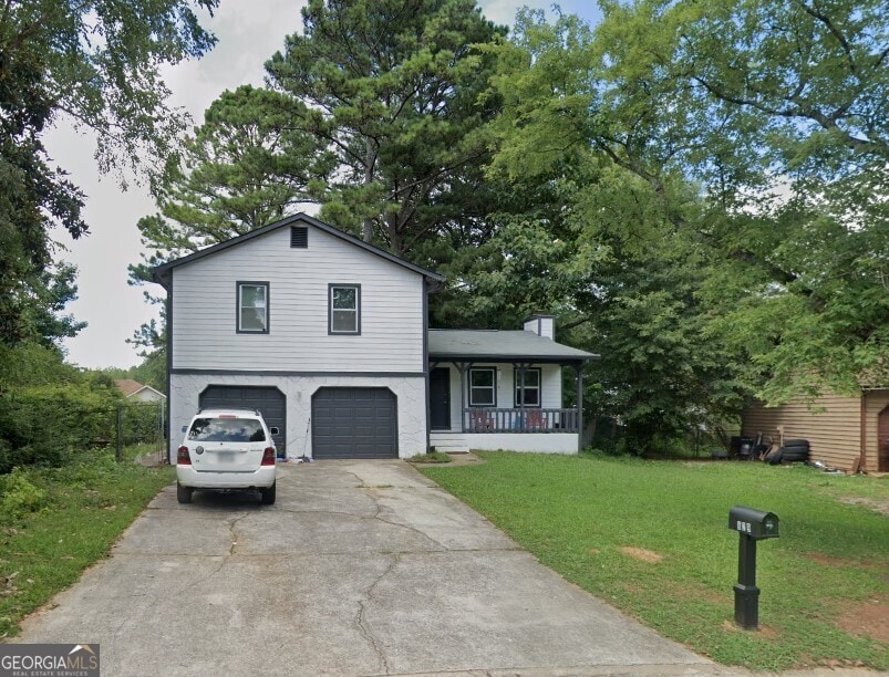 tri-level home featuring a front yard, a porch, and a garage