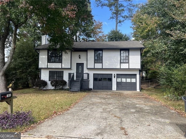 raised ranch with a front lawn and a garage