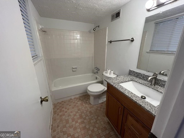 full bathroom featuring tile patterned floors, vanity, a textured ceiling, tiled shower / bath combo, and toilet