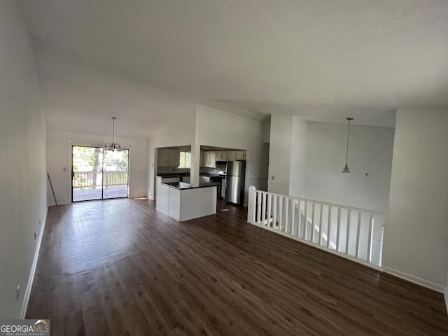 unfurnished living room with a notable chandelier, dark hardwood / wood-style floors, and vaulted ceiling