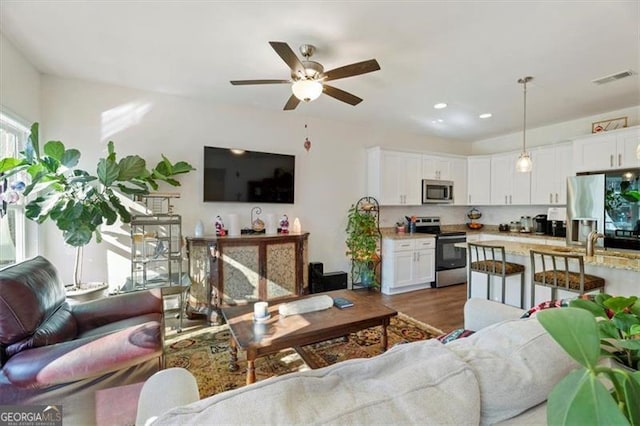 living room with ceiling fan, sink, and dark hardwood / wood-style floors