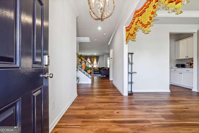 entryway with a chandelier, crown molding, and dark wood-type flooring