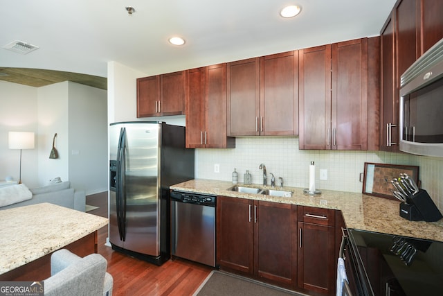 kitchen with light stone countertops, appliances with stainless steel finishes, dark hardwood / wood-style flooring, backsplash, and sink