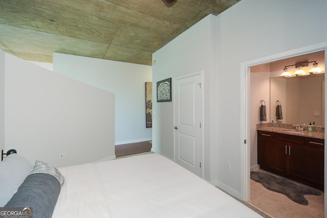 carpeted bedroom with sink and ensuite bath