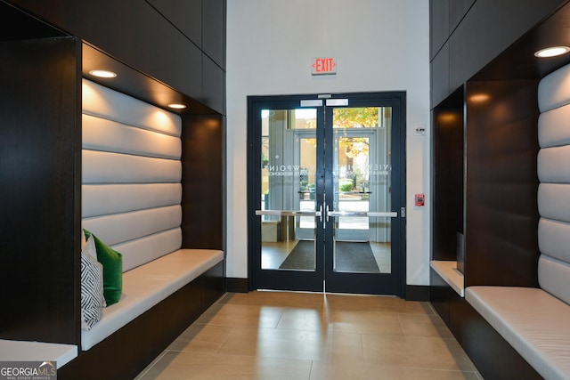 interior space with light tile patterned floors, a high ceiling, and french doors