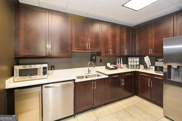 kitchen with a paneled ceiling, sink, light tile patterned floors, and stainless steel appliances