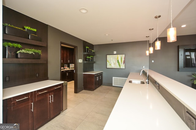 kitchen with decorative light fixtures, light tile patterned flooring, dark brown cabinetry, and sink