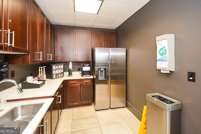 kitchen with a drop ceiling, stainless steel fridge with ice dispenser, sink, and light tile patterned floors