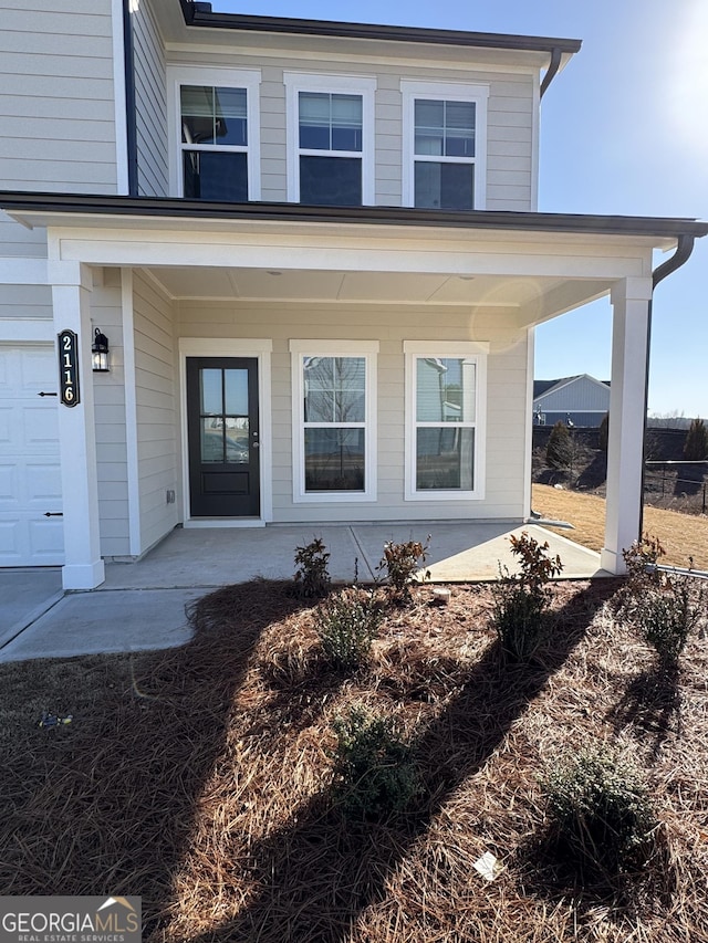 property entrance with a garage and covered porch