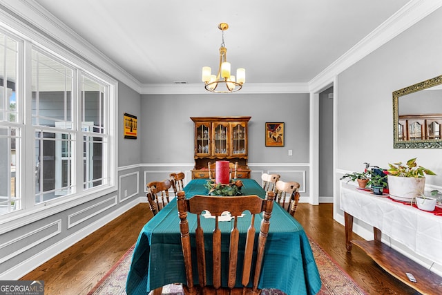 dining space with crown molding, dark wood-type flooring, and an inviting chandelier