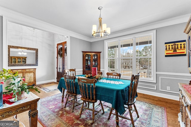 dining area with a notable chandelier, wood-type flooring, and ornamental molding