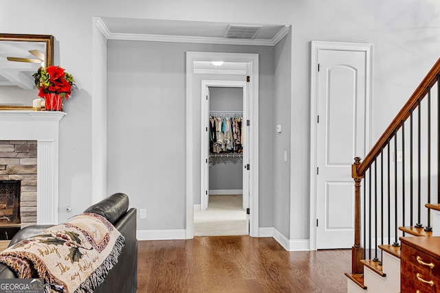 interior space with ornamental molding, a stone fireplace, and dark wood-type flooring