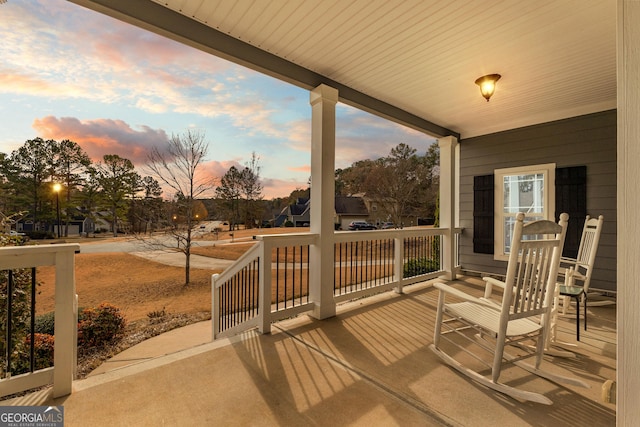 deck at dusk featuring covered porch