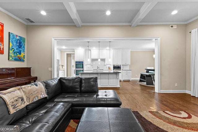 living room with beamed ceiling, dark hardwood / wood-style floors, crown molding, and sink