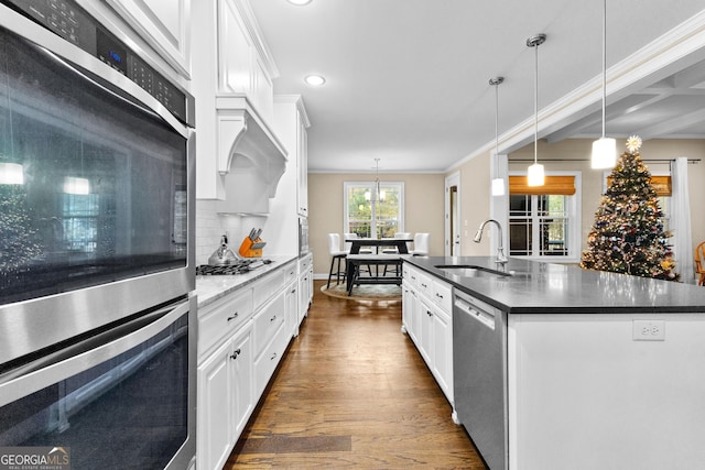 kitchen with appliances with stainless steel finishes, sink, a center island with sink, dark hardwood / wood-style floors, and white cabinetry