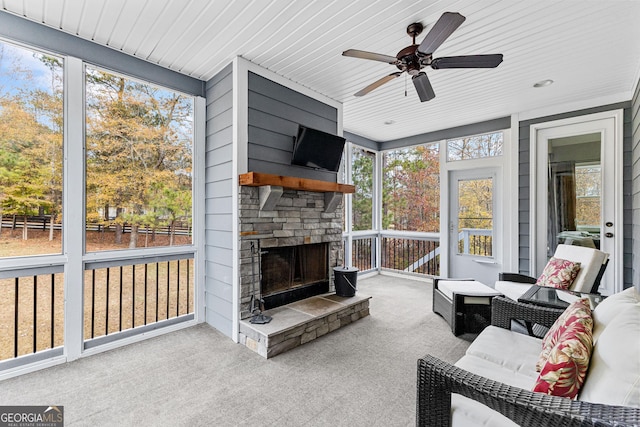 sunroom with ceiling fan, wood ceiling, and an outdoor stone fireplace