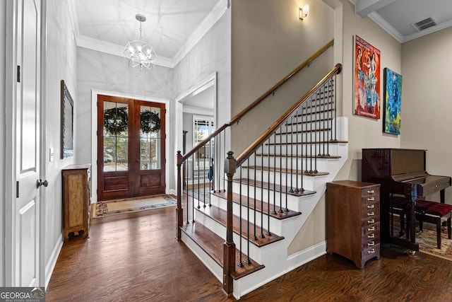 foyer with an inviting chandelier, crown molding, dark wood-type flooring, and french doors