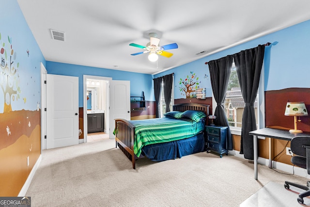 bedroom featuring ceiling fan, ensuite bathroom, and light colored carpet