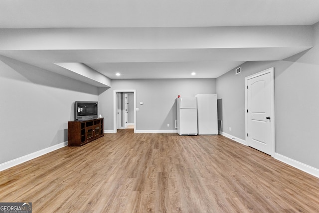 basement with white fridge and light wood-type flooring