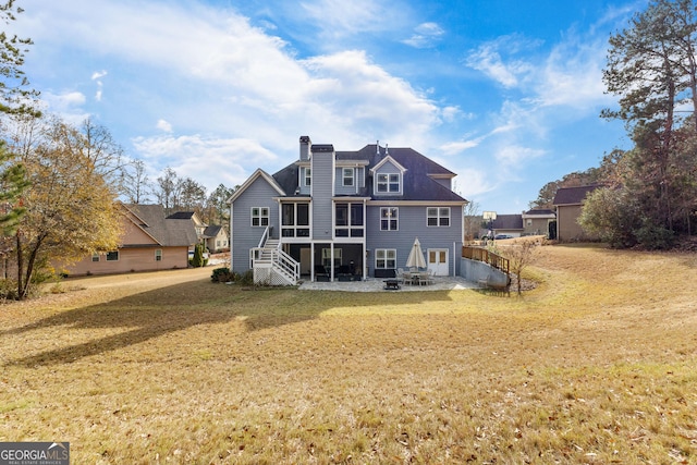 rear view of property with a lawn and a sunroom