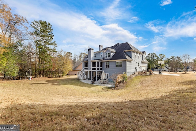 rear view of house with a lawn, a sunroom, and a garage