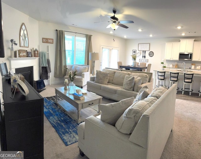 living room featuring ceiling fan, sink, and light carpet