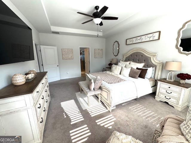 carpeted bedroom featuring ceiling fan and a tray ceiling