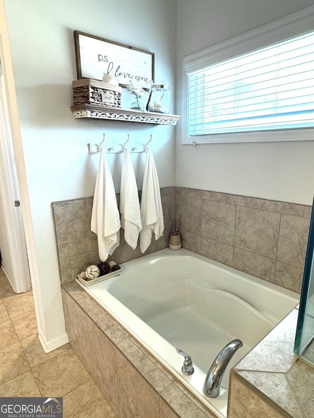 bathroom with tiled tub and tile patterned flooring