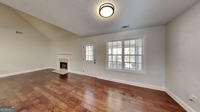 unfurnished living room with a textured ceiling, lofted ceiling, and dark wood-type flooring