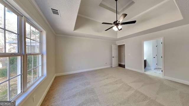 unfurnished bedroom with light carpet, a tray ceiling, multiple windows, and ceiling fan