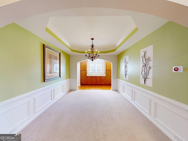 interior space featuring a raised ceiling, crown molding, and a chandelier