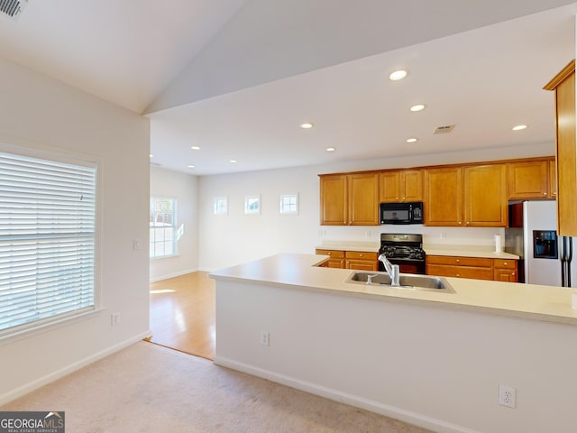 kitchen with lofted ceiling, sink, gas range oven, light colored carpet, and fridge with ice dispenser