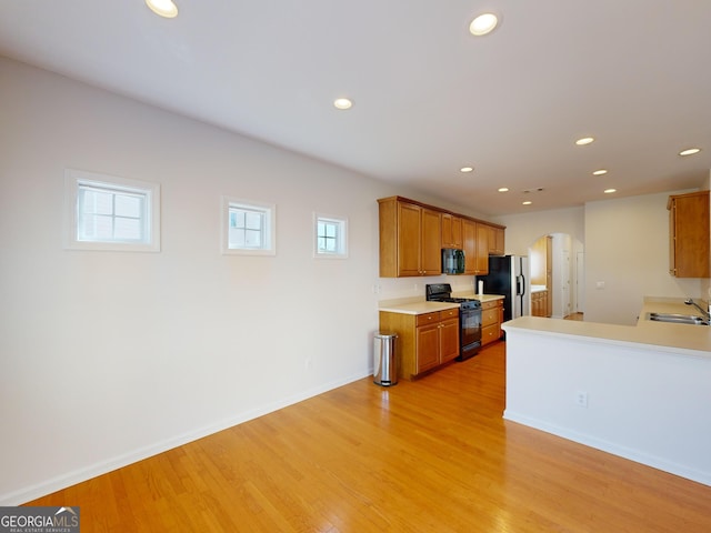 kitchen featuring sink, plenty of natural light, black appliances, and light wood-type flooring