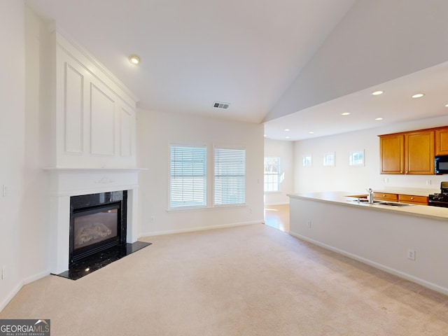 unfurnished living room featuring light carpet, sink, and high vaulted ceiling