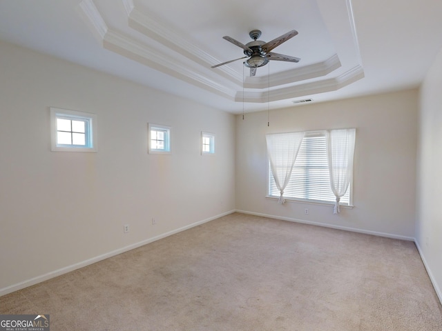 empty room featuring ceiling fan, crown molding, light carpet, and a tray ceiling