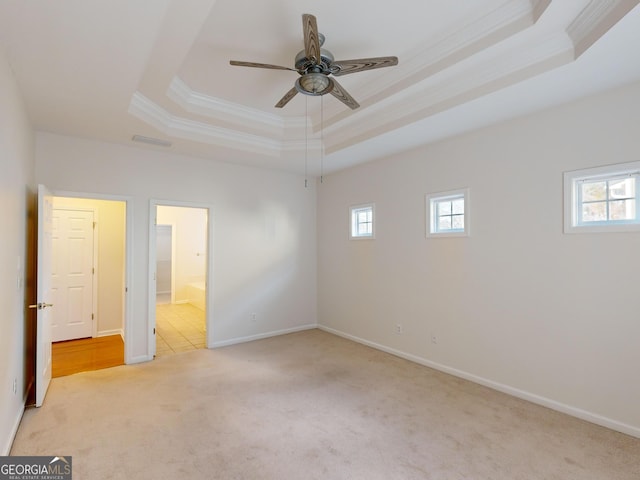 carpeted spare room with ceiling fan, crown molding, and a tray ceiling