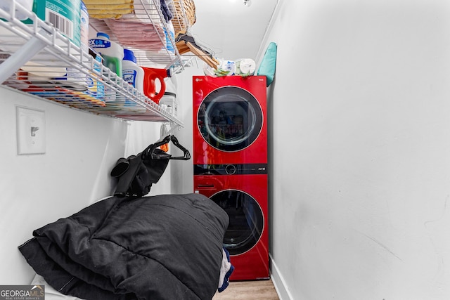 clothes washing area with hardwood / wood-style floors and stacked washer / drying machine