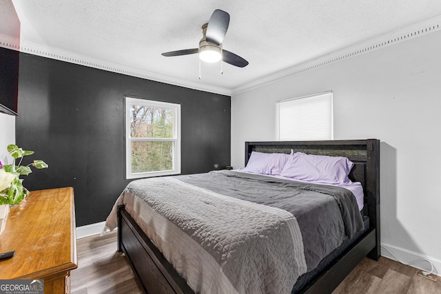 bedroom featuring a textured ceiling, ceiling fan, crown molding, and dark hardwood / wood-style floors