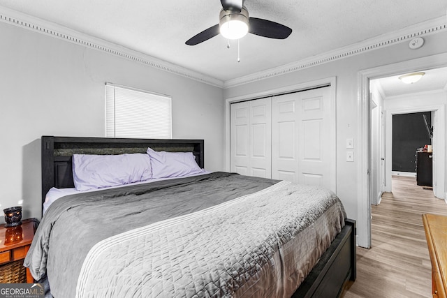 bedroom featuring ornamental molding, a textured ceiling, ceiling fan, light hardwood / wood-style flooring, and a closet