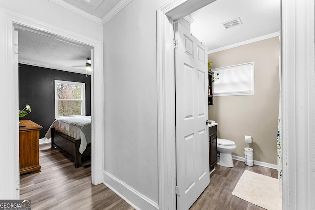 bathroom featuring vanity, crown molding, hardwood / wood-style flooring, ceiling fan, and toilet