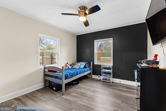 bedroom with multiple windows, hardwood / wood-style floors, and ceiling fan