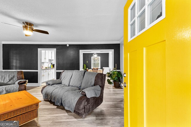 living room featuring light hardwood / wood-style floors, ceiling fan, and crown molding