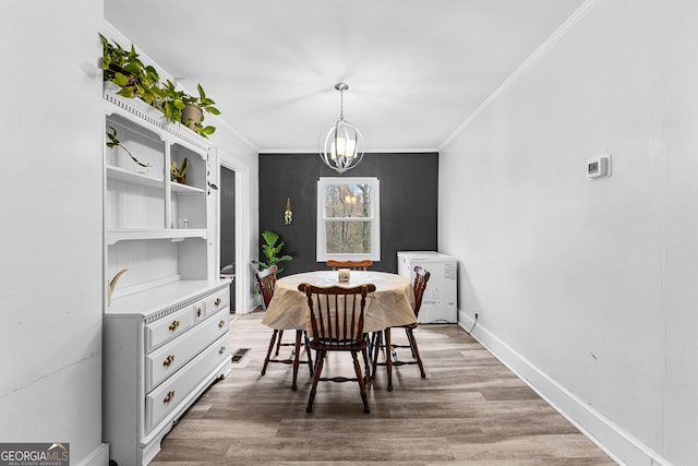 dining room featuring an inviting chandelier, wood-type flooring, and ornamental molding