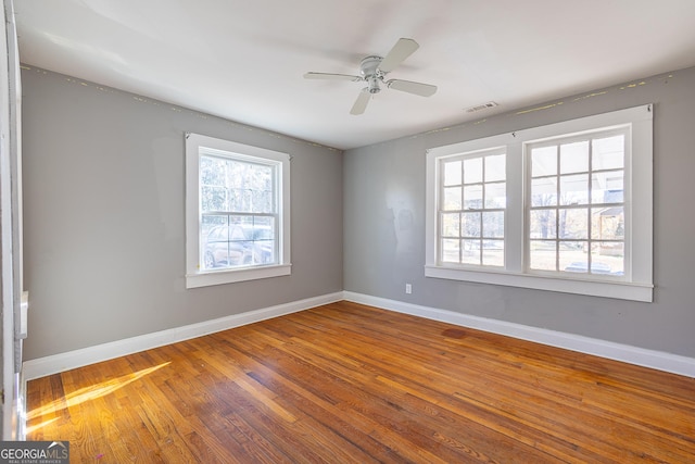 empty room with ceiling fan, wood-type flooring, and a wealth of natural light