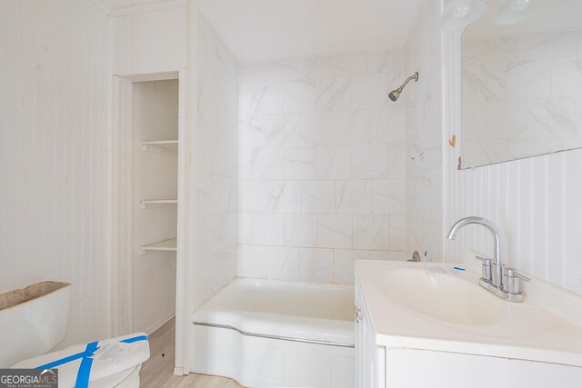 full bathroom with hardwood / wood-style flooring, tiled shower / bath combo, toilet, and vanity