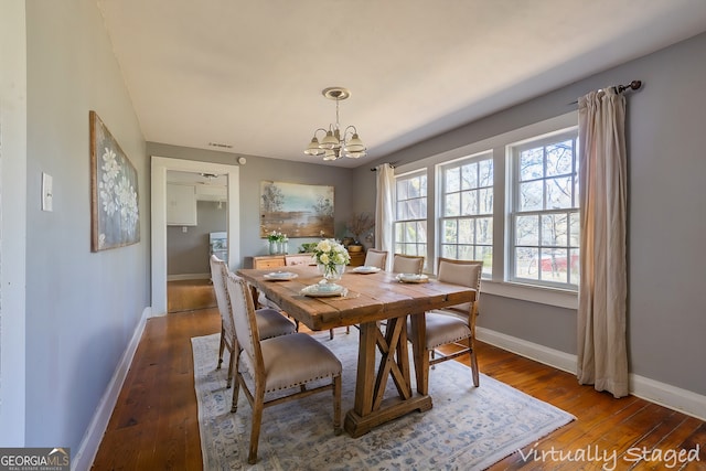 dining space featuring dark hardwood / wood-style flooring and a chandelier