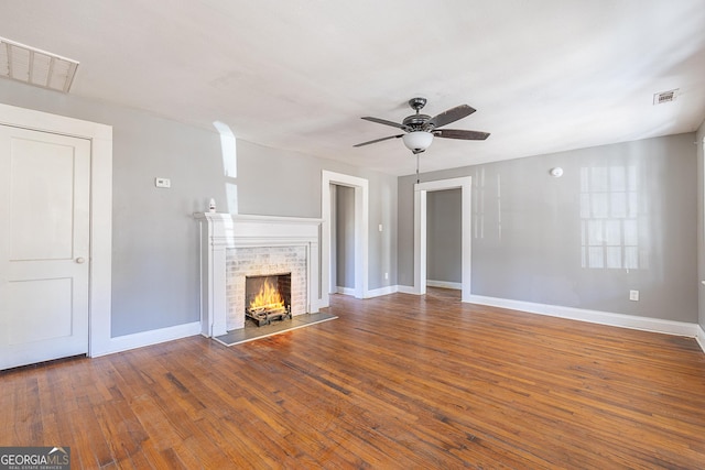 unfurnished living room featuring ceiling fan, dark wood-type flooring, and a brick fireplace