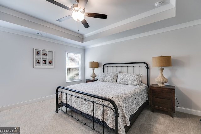 carpeted bedroom featuring a tray ceiling, ceiling fan, and crown molding