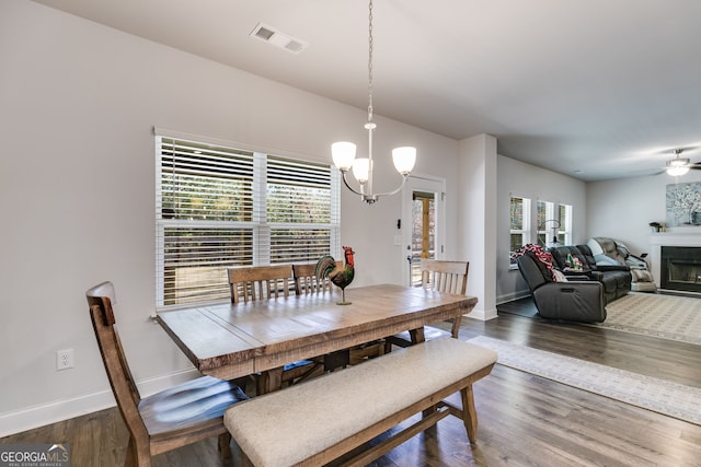 dining area with ceiling fan with notable chandelier, dark hardwood / wood-style flooring, and a wealth of natural light