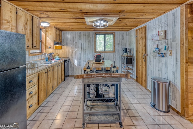 kitchen with wood walls, black refrigerator, wood ceiling, and sink